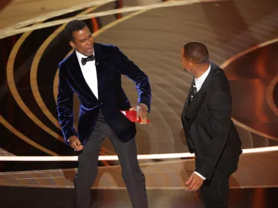 Chris Rock reacts after being hit by Will Smith (R) as Rock spoke on stage during the 94th Academy Awards in Hollywood, Los Angeles, California, U.S., March 27, 2022. REUTERS/Brian Snyder