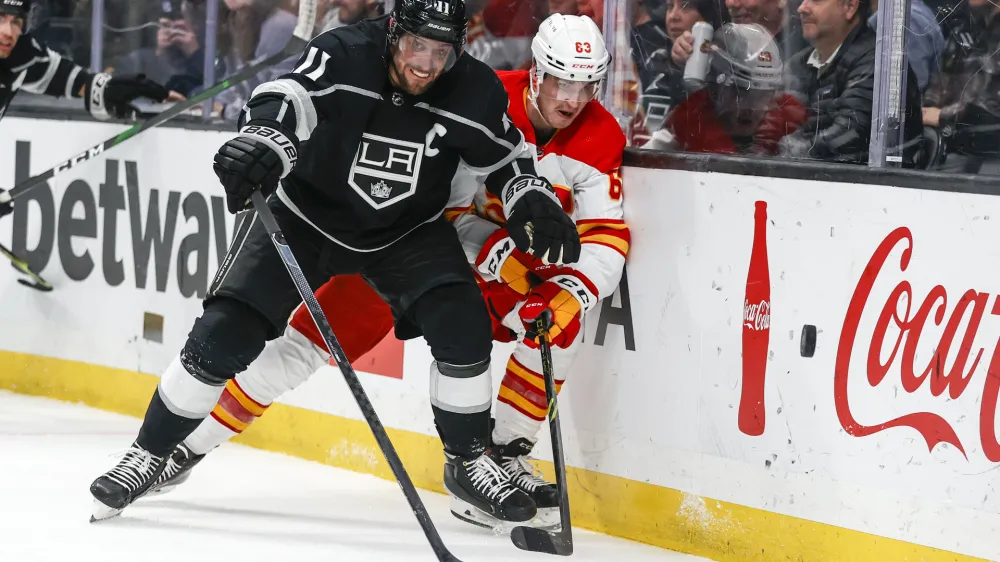 Los Angeles Kings forward Anze Kopitar (11) and Calgary Flames forward Adam Ruzicka (63) vie for the puck during the second period of an NHL hockey game Monday, April 4, 2022, in Los Angeles. (AP Photo/Ringo H.W. Chiu)