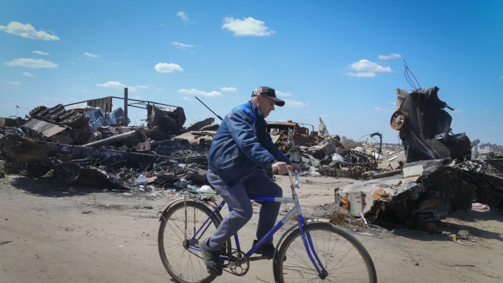 A local residence rides a bike past a destroyed Russian military vehicle in Bucha, on the outskirts of Kyiv, Ukraine, Tuesday, May 10, 2022. (AP Photo/Efrem Lukatsky)