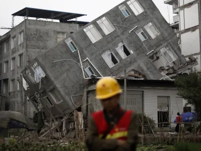 A rescuer walks in front of a damaged building after Saturday's earthquake in Lingguan town of Baoxing county, Sichuan province April 22, 2013. Rescuers struggled to reach a remote, rural corner of southwestern China on Sunday as the toll of the dead and missing from the country's worst earthquake in three years climbed to 208 with almost 1,000 serious injuries. The 6.6 magnitude quake struck in Lushan county, near the city of Ya'an in the southwestern province of Sichuan, close to where a devastating 7.9 quake hit in May 2008, killing 70,000. REUTERS/Aly Song (CHINA - Tags: DISASTER ENVIRONMENT TPX IMAGES OF THE DAY)