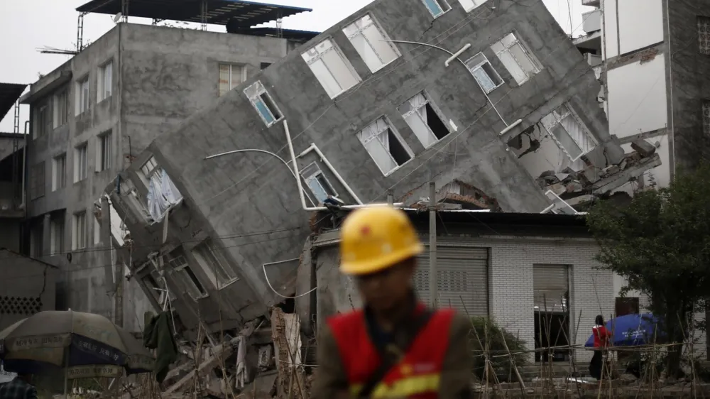 A rescuer walks in front of a damaged building after Saturday's earthquake in Lingguan town of Baoxing county, Sichuan province April 22, 2013. Rescuers struggled to reach a remote, rural corner of southwestern China on Sunday as the toll of the dead and missing from the country's worst earthquake in three years climbed to 208 with almost 1,000 serious injuries. The 6.6 magnitude quake struck in Lushan county, near the city of Ya'an in the southwestern province of Sichuan, close to where a devastating 7.9 quake hit in May 2008, killing 70,000. REUTERS/Aly Song (CHINA - Tags: DISASTER ENVIRONMENT TPX IMAGES OF THE DAY)