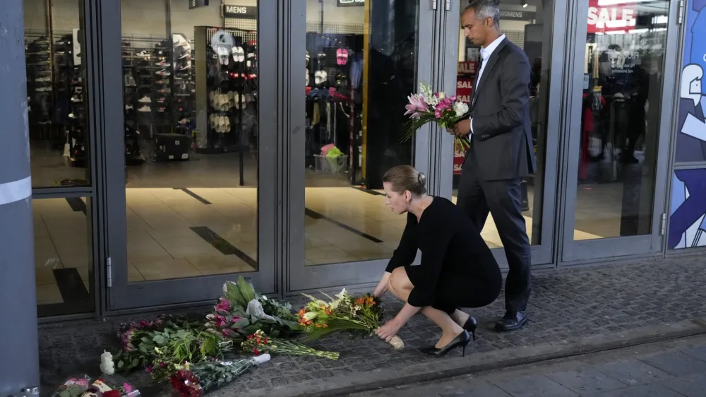 Danish Prime Minister Mette Frederiksen, bottom, and Minister of justice Mattias Tesfaye lay flowers at the entrance of the Field's shopping center in Copenhagen, Denmark, Monday, July 4, 2022. Danish police believe a shopping mall shooting that left three people dead and four others seriously wounded was not terror-related. They said Monday that the gunman acted alone and appears to have selected his victims at random. (AP Photo/Sergei Grits)
