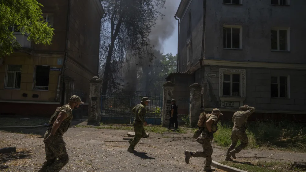 FILE - Ukrainian soldiers run after a missile strike hit a residential area, in Kramatorsk, Donetsk region, eastern Ukraine, Thursday, July 7, 2022. Injured residents sat dazed and covered in blood. A crater was now the centre of the courtyard. Last week, the governor of the Donetsk oblast Pavlo Kyrylenko urged the province's more than 350,000 remaining residents to flee to safer towns further West, saying that evacuating the region was necessary to save lives and allow the Ukrainian army to better defend towns against a Russian advance. Many refuse to leave the city. (AP Photo/Nariman El-Mofty, File)