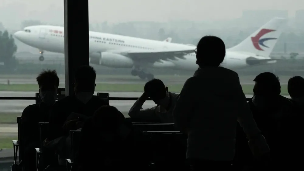 FILE - Passengers wait for their flight as a China Eastern flight takes off from the runway of Baiyun Airport on Friday, March 25, 2022, in southern China's Guangzhou province. The National Transportation Safety Board said the team departed for China on Friday, April 1, to participate in the Civil Aviation Administration of China's investigation of the March 21 crash of a China Eastern Airlines Boeing 737-800 in which all 132 people on board were killed. (AP Photo/Ng Han Guan, File)
