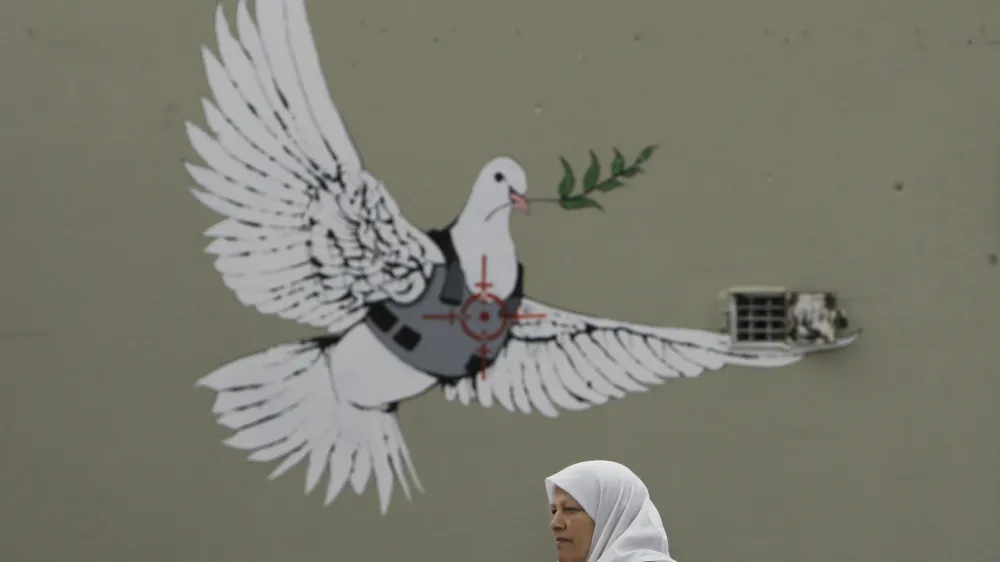A work by English graffiti artist Banksy is seen on a wall in the West Bank town of Bethlehem, Friday, Dec. 21, 2007. Two other works by the British artist in the biblical West Bank town were defaced by locals after some found the work offensive, Palestinian sources said. (AP Photo/Kevin Frayer)