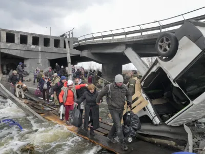 People cross an improvised path under a destroyed bridge while fleeing the town of Irpin close to Kyiv, Ukraine, Monday, March 7, 2022.Russia announced yet another cease-fire and a handful of humanitarian corridors to allow civilians to flee Ukraine. Previous such measures have fallen apart and Moscow's armed forces continued to pummel some Ukrainian cities with rockets Monday. (AP Photo/Efrem Lukatsky)