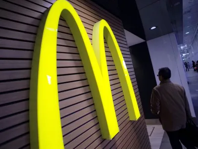 FILE - In this Dec. 17, 2014 file photo, a man walks by a McDonald's logo in front of its restaurant in Tokyo. McDonalds is set to unveil its latest plans to revive its sputtering business on Monday, May 4, 2015. (AP Photo/Eugene Hoshiko, File)
