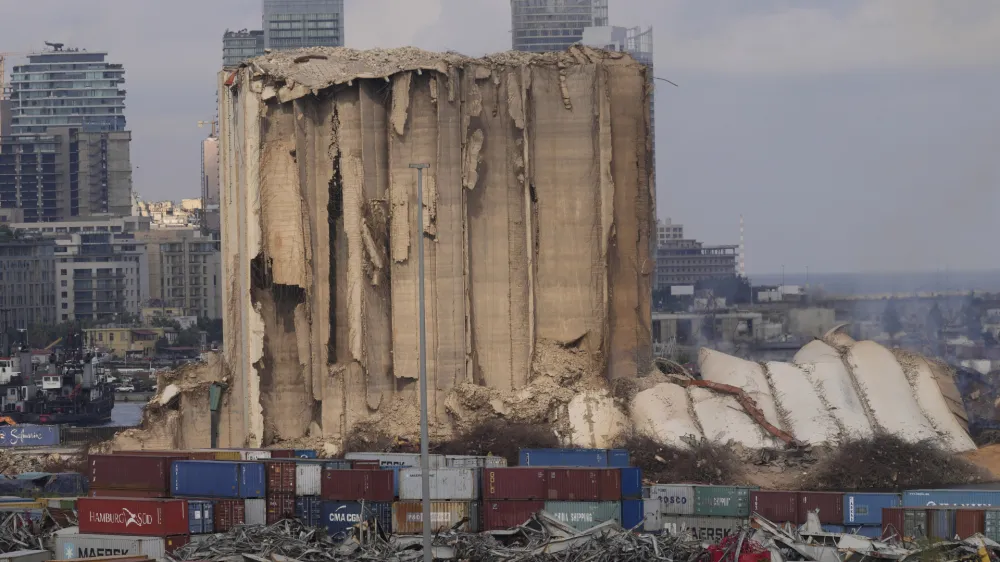 A collapsed portion, right, lies on the ground of the silos that damaged during the August 2020 massive explosion in the port, in Beirut, Lebanon, Tuesday, Aug. 23, 2022. The ruins of the Beirut Port silos' northern block that withstood a devastating port explosion two years ago has collapsed. The smoldering structure fell over on Tuesday morning into a cloud of dust, leaving the southern block standing next to a pile of charred ruins. (AP Photo/Hussein Malla)