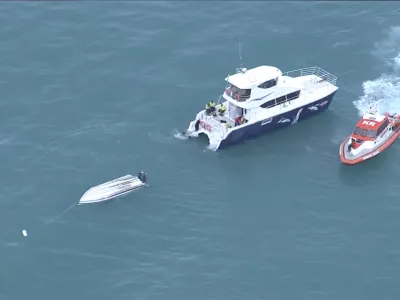 An aerial view shows two rescue boats alongside a capsized boat Saturday, Sept. 10, 2022, Kaikoura, New Zealand. Five people in New Zealand died Saturday after the small charter boat they were aboard capsized, authorities say, in what may have been a collision with a whale. Another six people aboard the boat were rescued. (TVNZ via AP)