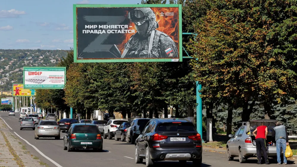 Vehicles drive past advertising boards, including panels displaying pro-Russian slogans, in a street in the course of Russia-Ukraine conflict in Luhansk, Ukraine September 20, 2022. One of the boards reads: "World changes - truth stays. Army of Russia". REUTERS/Alexander Ermochenko