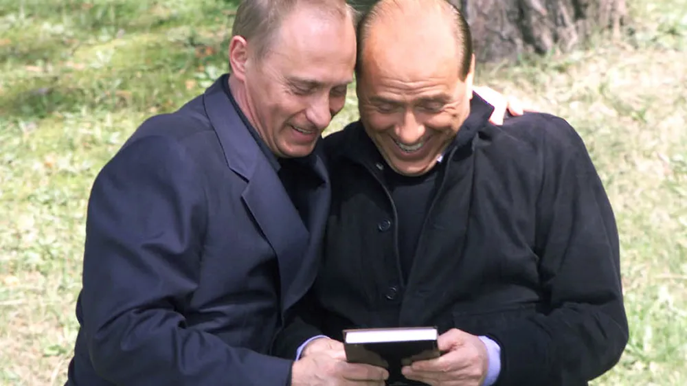Russian President Vladimir Putin, left, presents Italian Prime Minister Silvio Berlusconi with the book "Berlusconi's Effect," published in Russia, during their informal meeting in the Bocharov Ruchei residence in the Black Sea resort of Sochi, southern Russia, Tuesday, April 2, 2002. Berlusconi, who arrived in Sochi on Tuesday afternoon for his fourth visit with Putin, is the first Western European leader to meet with Putin in his Bocharov Ruchei residence. (AP Photo/ITAR-TASS, Presidential Press Service)