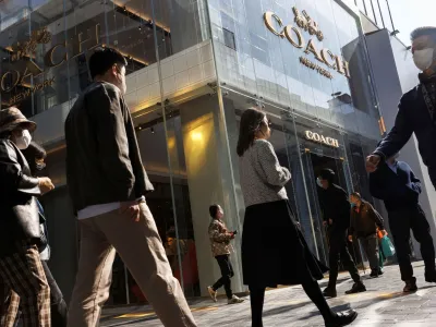 People walk past a store of the Coach luxury fashion retailer in a shopping district in Beijing, China, October 19, 2022. REUTERS/Thomas Peter