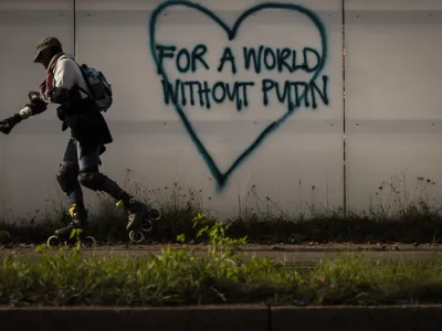 A man rollerskates past a graffiti reading "For a world without Putin" in Zurich, Switzerland on Saturday October 29, 2022. (Michael Buholzer/Keystone via AP)