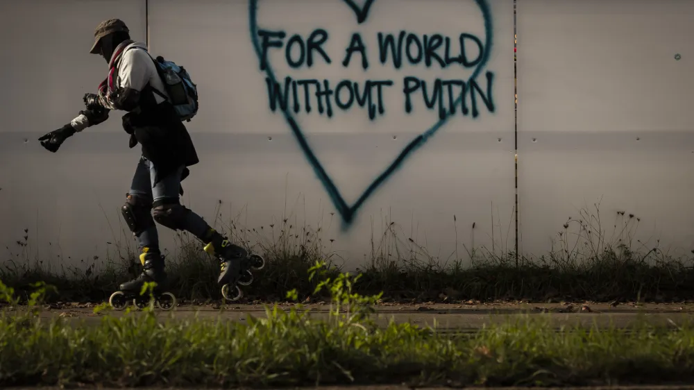 A man rollerskates past a graffiti reading "For a world without Putin" in Zurich, Switzerland on Saturday October 29, 2022. (Michael Buholzer/Keystone via AP)