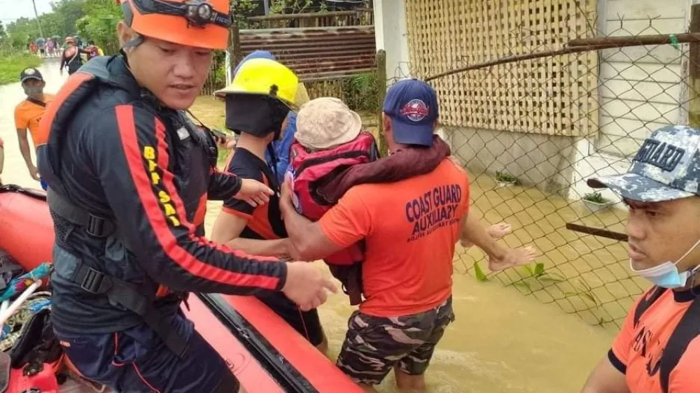 Rescue personnel assist a person onto a rescue boat along a flooded road, after the tropical storm Megi hit in Capiz Province, Philippines April 12, 2022. Philippine Coast Guard/Handout via REUTERS THIS IMAGE HAS BEEN SUPPLIED BY A THIRD PARTY. MANDATORY CREDIT. NO RESALES. NO ARCHIVES