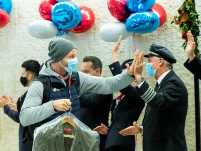 A man gives a high five to the crew members as he exits baggage claim after landing in the British Airways flight at JFK International Airport in New York, U.S., November 8, 2021. REUTERS/Eduardo Munoz