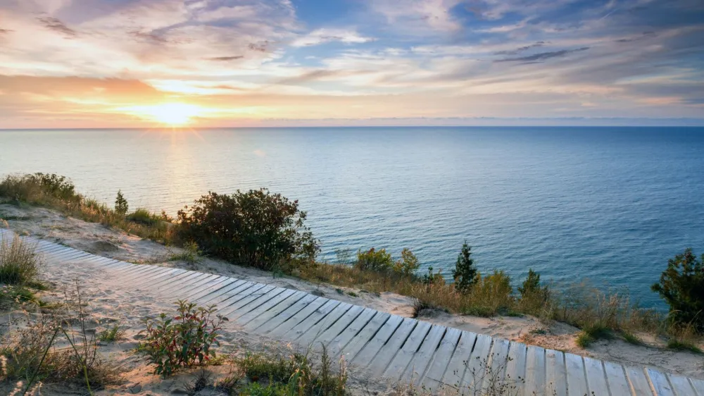 A colorful sunset over Lake Michigan shines its light on this boardwalk on Empire Bluff Trail near Empire Michigan. This trail overlooks Sleeping Bear Dunes
