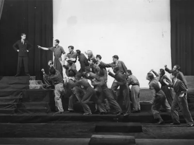 Krstna uprizoritev Delakove dramatizacije Hlapca Jerneja, podnaslovljene &raquo;Igra z narodom: kolektivna drama&laquo;. V avtorjevi režiji in izvedbi Delavskega odra v Ljubljani so jo premierno uprizorili 23. maja 1932. Ikonoteka SLOGI &ndash; Gledali&scaron;ki muzej.