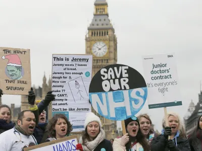 Junior National Health Service (NHS) doctors wave placards referring to British Conservative Party Secretary of State for Health, Jeremy Hunt, during a protest outside St Thomas Hospital in London, Wednesday, Feb. 10, 2016, backdropped by the Houses of Parliament and Big Ben's clock tower. Thousands of junior doctors have walked off the job in England in a dispute over pay and working conditions. (AP Photo/Frank Augstein)