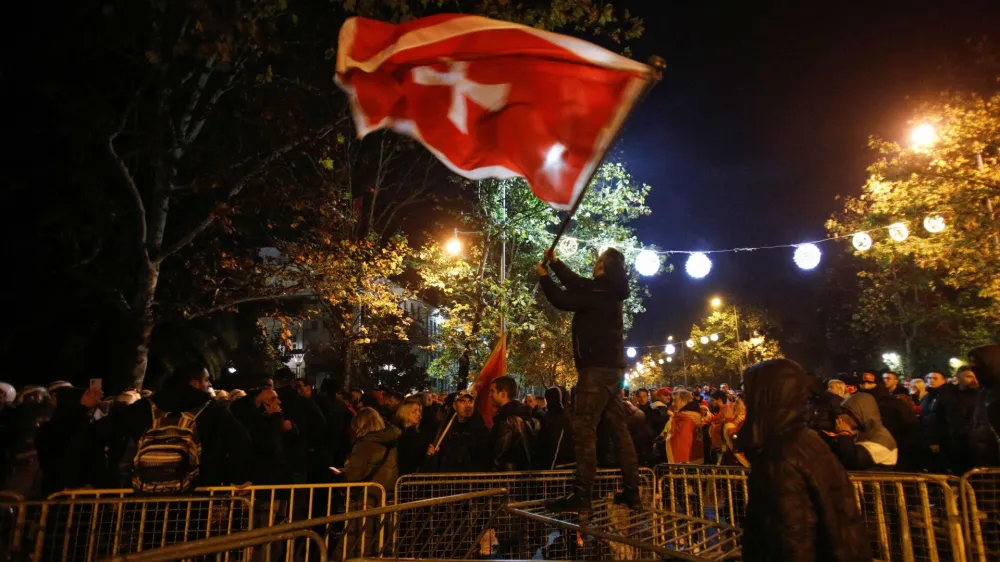 A protestor waves a flag on top of the breached barrier during a protest against the adoption of a law to limit presidential powers in Podgorica, Montenegro, December 12, 2022. REUTERS/Stevo Vasiljevic