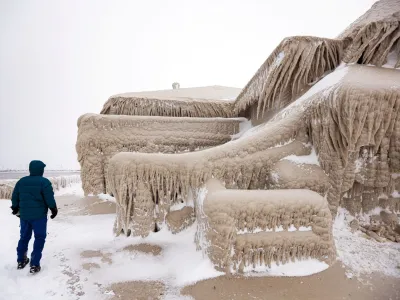 A man walks beside ice formed by the spray of Lake Erie waves which covered a restaurant during a winter storm in Hamburg, New York, U.S., December 26, 2022. REUTERS/Lindsey DeDario   TPX IMAGES OF THE DAY