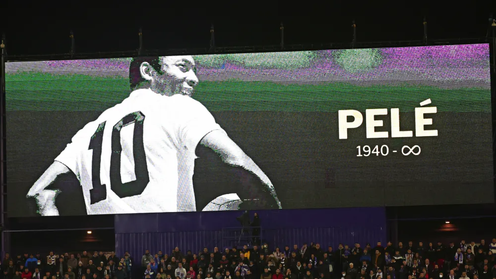 Fans sit beneath a giant screen during a minute of silence for Pel&eacute; before the start of a Spanish La Liga soccer match between Valladolid and Real Madrid at the Jose Zorrilla stadium in Valladolid, Spain, Friday, Dec. 30, 2022. Pel&eacute;, the Brazilian king of soccer who won a record three World Cups and became one of the most commanding sports figures of the last century, died in Sao Paulo on Thursday. He was 82. (AP Photo/Pablo Garcia)