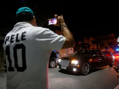 A fan wearing a shirt with Brazilian soccer legend Pele's name on it, records images as a vehicle transports Pele's body, near the Vila Belmiro stadium in Santos, Brazil, January 2, 2023. REUTERS/Diego Vara
