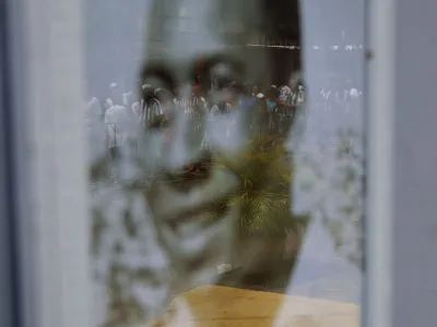 Soccer Football - Death of Brazilian soccer legend Pele - Vila Belmiro Stadium, Santos, Brazil - January 2, 2023 Mourners queuing to pay their respect to Brazilian soccer legend Pele are seen in the reflection on a portrait of Pele hanging outside a house near his former club Santos' Vila Belmiro stadium REUTERS/Ricardo Moraes