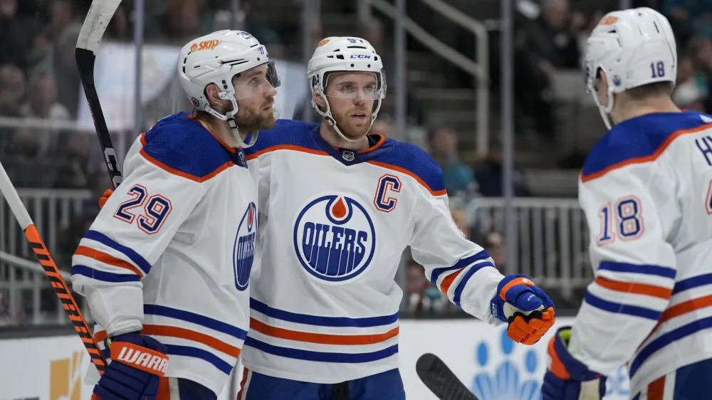 Edmonton Oilers center Connor McDavid, middle, celebrates with center Leon Draisaitl, left, and left wing Zach Hyman after scoring against the San Jose Sharks during the second period of an NHL hockey game in San Jose, Calif., Friday, Jan. 13, 2023. (AP Photo/Godofredo A. V&aacute;squez)
