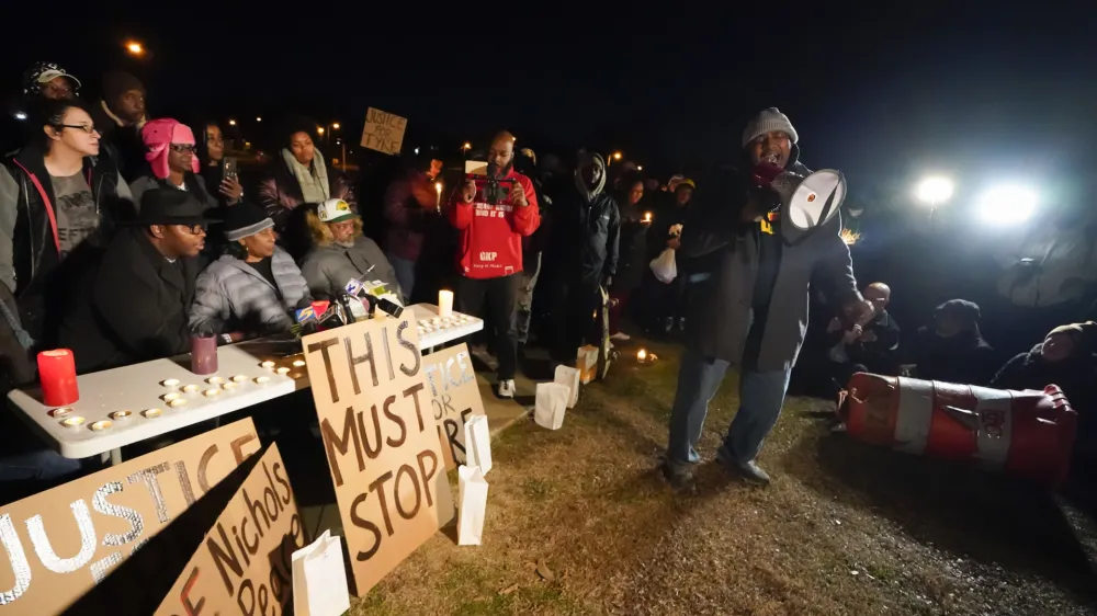 Rev. Andre E Johnson, of the Gifts of Life Ministries, preaches at a candlelight vigil for Tyre Nichols, who died after being beaten by Memphis police officers, in Memphis, Tenn., Thursday, Jan. 26, 2023. Behind him, seated center, are Tyre's mother RowVaughn Wells and his stepfather Rodney Wells. (AP Photo/Gerald Herbert)