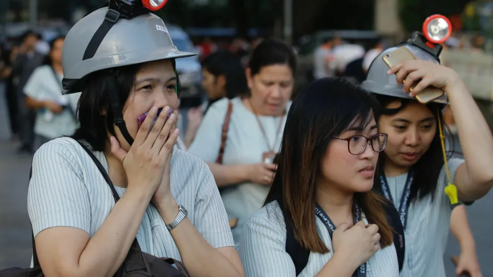 Wearing protective helmets, employees evacuate their office building following an earthquake in Manila, Philippines Monday, April 22, 2019. A strong earthquake has shaken the area around the Philippine capital, prompting thousands of people to flee to safety. There were no immediate reports of injuries or widespread damage. The U.S. Geological Survey says the magnitude 6.3 quake struck northwest of Manila near the town of Gutad on Luzon island. (AP Photo/Aaron Favila)