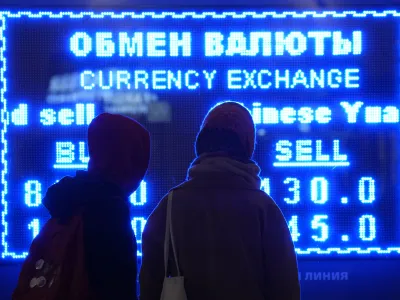 Women look at a screen displaying exchange rate at a currency exchange office in St. Petersburg, Russia, Tuesday, March 1, 2022. The Russian currency plunged about 30% against the U.S. dollar Monday after Western nations announced moves to block some Russian banks from the SWIFT international payment system and to restrict Russia's use of its massive foreign currency reserves. (AP Photo/Dmitri Lovetsky)