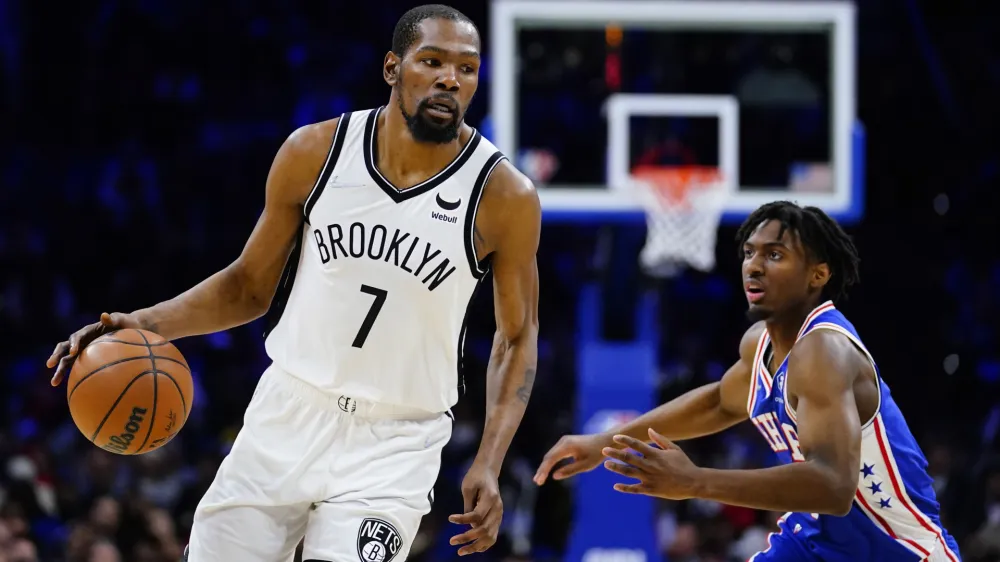 Brooklyn Nets' Kevin Durant, left, dribbles past Philadelphia 76ers' Tyrese Maxey during the second half of an NBA basketball game, Thursday, March 10, 2022, in Philadelphia. (AP Photo/Matt Slocum)