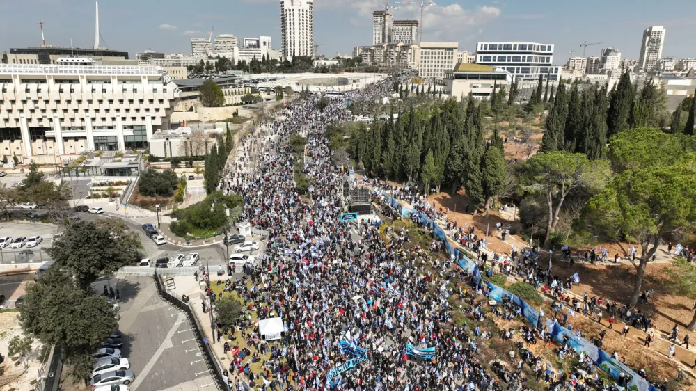 An aerial view shows Israelis holding flags as they demonstrate on the day Israel's constitution committee is set to start voting on changes that would give politicians more power on selecting judges while limiting Supreme Court powers to strike down legislation, in front of the Knesset, Israel's parliament in Jerusalem, February 13, 2023. REUTERS/Ilan Rosenberg