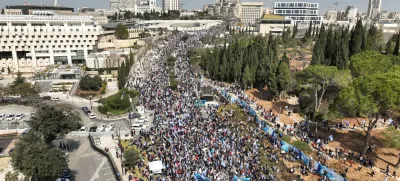 An aerial view shows Israelis holding flags as they demonstrate on the day Israel's constitution committee is set to start voting on changes that would give politicians more power on selecting judges while limiting Supreme Court powers to strike down legislation, in front of the Knesset, Israel's parliament in Jerusalem, February 13, 2023. REUTERS/Ilan Rosenberg