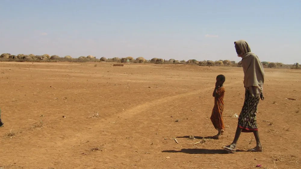 A man and his child passes the carcass of a cow in Denan, Ethiopia, 1,400 kilometers south east of the capital Addis Ababa, Monday, Jan. 16, 2006, which has been hit by a severe drought, and the U.N says 11 million people in the Horn of Africa region are on the brink of starvation. Denan was the scene of a catastrophic drought in 2000 and some 10,000 people are still living in a makeshift camp in Denan six-years later. (AP Photo/Anthony Mitchell)