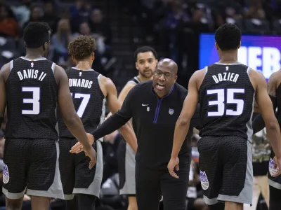 Sacramento Kings coach Mike Brown greets guard Terence Davis (3) and guard PJ Dozier (35) during a timeout in the first half of the team's NBA basketball game against the Golden State Warriors in Sacramento, Calif., Friday, April 7, 2023. (AP Photo/Jos&eacute; Luis Villegas)