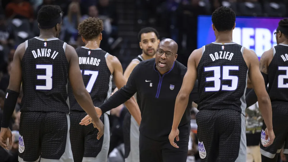 Sacramento Kings coach Mike Brown greets guard Terence Davis (3) and guard PJ Dozier (35) during a timeout in the first half of the team's NBA basketball game against the Golden State Warriors in Sacramento, Calif., Friday, April 7, 2023. (AP Photo/Jos&eacute; Luis Villegas)