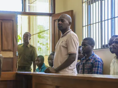 Pastor Paul Mackenzie (na fotografiji stoji) pravi, da ni odgovoren za smrt več kot 80 sledilcev. Vztraja, da je cerkev zaprl že pred leti in da ni nikomur odrejal, naj strada na poti do večnega življenja.&nbsp;