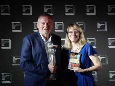 Bulgarian writer Georgi Gospodinov, left, holds up the winner's trophy after his book "Time Shelter" translated from Bulgarian by Angela Rodel, right, won The International Booker Prize 2023, in London, Tuesday, May 23, 2023. (AP Photo/Kirsty Wigglesworth)