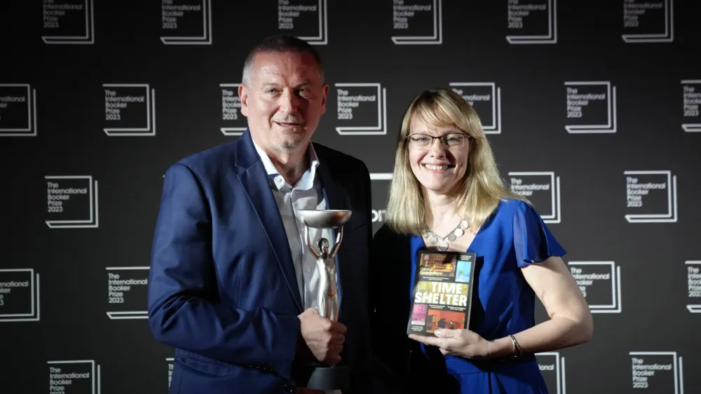 Bulgarian writer Georgi Gospodinov, left, holds up the winner's trophy after his book "Time Shelter" translated from Bulgarian by Angela Rodel, right, won The International Booker Prize 2023, in London, Tuesday, May 23, 2023. (AP Photo/Kirsty Wigglesworth)