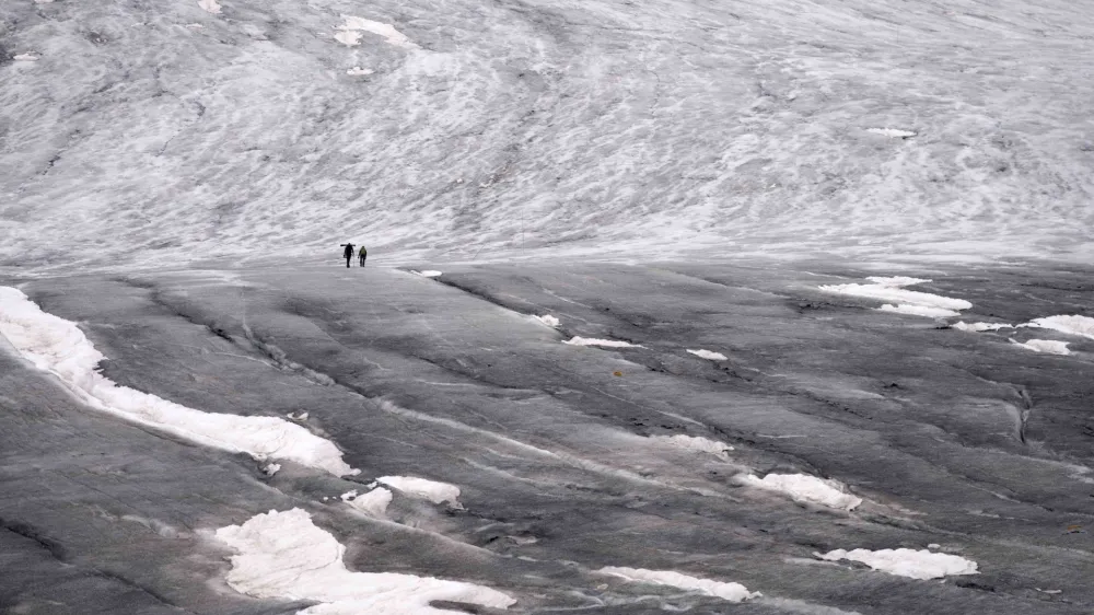 Team members of ETH (Swiss Federal Institute of Technology) glaciologist and head of the Swiss measurement network 'Glamos', Matthias Huss, arrive at the Rhone Glacier to take measurements near Goms, Switzerland, Friday, June 16, 2023. (AP Photo/Matthias Schrader)