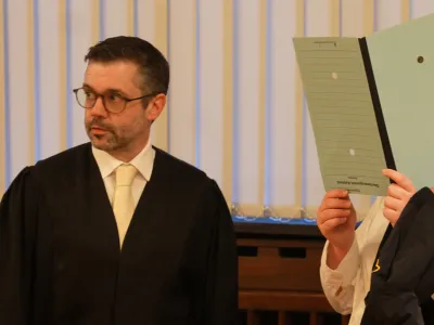 FILED - 11 January 2023, Rheinland-Pfalz, Koblenz: The 37-year-old defendant (R) stands next to one of her lawyers in the courtroom of the Higher Regional Court. A German woman was convicted on Wednesday of membership of the Islamic State terrorist organization, crimes against humanity and aiding and abetting genocide. Photo: Thomas Frey/dpa - ACHTUNG: Die Angeklagte wurde auf Anweisung des Gerichts gepixelt