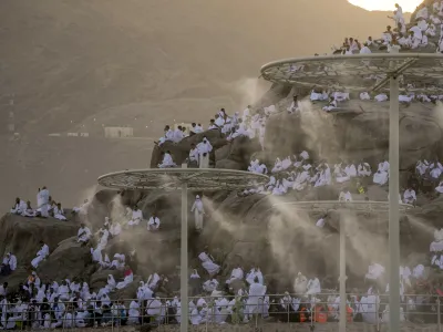 Water mist is sprayed on Muslim pilgrims as they pray on the rocky hill known as the Mountain of Mercy, on the Plain of Arafat, during the annual Hajj pilgrimage, near the holy city of Mecca, Saudi Arabia, Tuesday, June 27, 2023. Around two million pilgrims are converging on Saudi Arabia's holy city of Mecca for the largest Hajj since the coronavirus pandemic severely curtailed access to one of Islam's five pillars. (AP Photo/Amr Nabil)