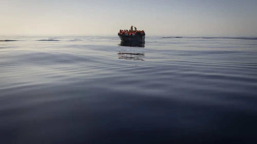 FILE - Migrants with life jackets provided by volunteers of the Ocean Viking, a migrant search and rescue ship run by NGOs SOS Mediterranee and the International Federation of Red Cross (IFCR), still sail in a wooden boat as they are being rescued, on Aug. 27,&nbsp;2022. The border and coast guard agency Frontex estimated that more than 50,300 attempts were made to enter the EU without authorization from January to May. It's more than double the number in the same period last year, and the most since 2017. (AP Photo/Jeremias Gonzalez, File)