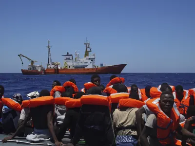 FILE - In this Thursday June 23, 2016 file photo, Migrants aboard a dinghy in the Mediterranean Sea wait to be rescued by members of the aid group Medecins Sans Frontieres (MSF) and the rescue group SOS Mediterranee Rescuers of SOS Mediterranee. Doctors Without Borders said Saturday, Aug. 12, 2017, it is temporarily suspending the activity of its rescue ship due to alleged threats from Libya&acirc;&euro;&trade;s coast guard, which has increasingly become more aggressive in patrolling the waters off its coasts where human traffickers launch boats crowded with migrants desperate to reach Europe. (AP Photo/Bram Janssen, File)