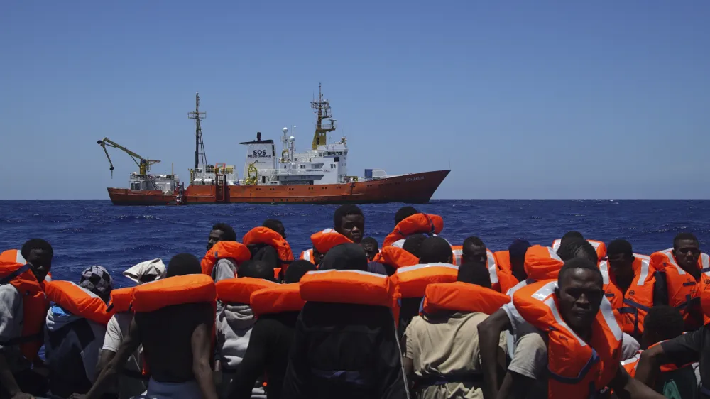 FILE - In this Thursday June 23, 2016 file photo, Migrants aboard a dinghy in the Mediterranean Sea wait to be rescued by members of the aid group Medecins Sans Frontieres (MSF) and the rescue group SOS Mediterranee Rescuers of SOS Mediterranee. Doctors Without Borders said Saturday, Aug. 12, 2017, it is temporarily suspending the activity of its rescue ship due to alleged threats from Libya&acirc;&euro;&trade;s coast guard, which has increasingly become more aggressive in patrolling the waters off its coasts where human traffickers launch boats crowded with migrants desperate to reach Europe. (AP Photo/Bram Janssen, File)