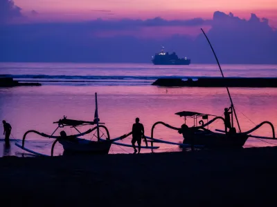 FILED - 14 November 2022, Indonesia, Nusa Dua: Men attach boats to the beach of Nusa Dua before sunrise on the day before the start of the G20 summit, with an Indonesian Navy ship visible in the background. Starting next year, tourists entering the Indonesian resort island of Bali will have to pay a fee of ten US dollars (nine euros) per person. Photo: Christoph Soeder/dpa
