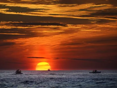 FILE - The sun rises over fishing boats in the Atlantic Ocean, Sept. 8, 2022, off of Kennebunkport, Maine. A system of ocean currents that carries heat northward across the North Atlantic could collapse during this century, according to a new study, and scientists have said before such a collapse could cause catastrophic sea-level rise and extreme weather across the globe. (AP Photo/Robert F. Bukaty, File)