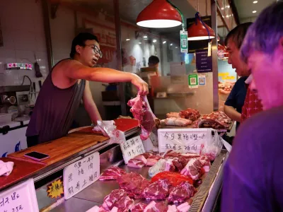 A pork vendor attends to a customer at a morning market in Beijing, China August 9, 2023. REUTERS/Tingshu Wang